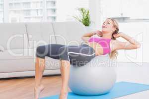 Smiling blonde doing sit ups with exercise ball