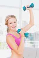 Athletic blonde lifting dumbbells and smiling