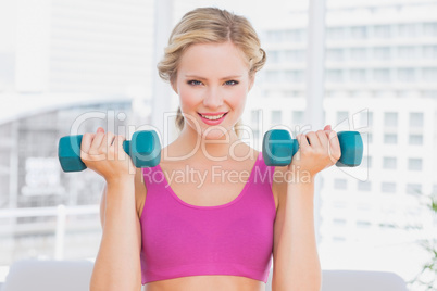 Cute blonde lifting dumbbells and smiling