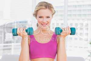 Cute blonde lifting dumbbells and smiling