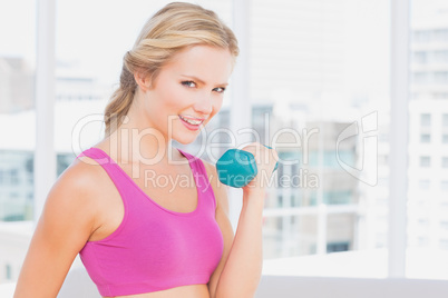 Pretty blonde lifting dumbbells and smiling at camera