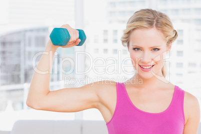 Happy blonde lifting dumbbell and flexing
