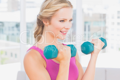 Happy blonde lifting dumbbells