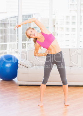 Fit blonde smiling at camera while stretching