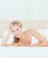 Cute blonde lying on her bed smiling at camera