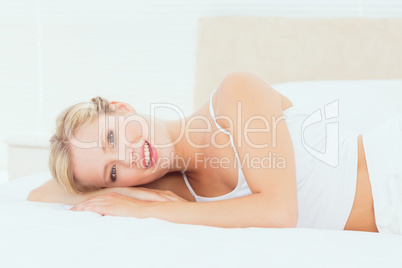 Natural blonde lying on her bed smiling at camera