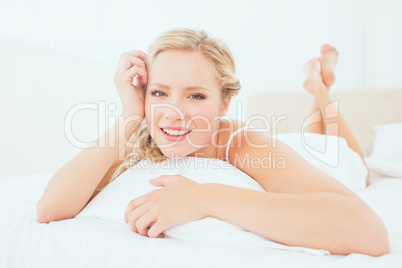 Natural young blonde lying on her bed smiling at camera