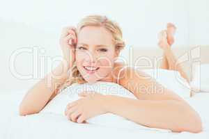 Natural young blonde lying on her bed smiling at camera