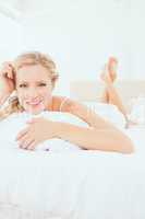 Content young blonde lying on her bed smiling at camera