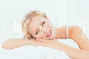 Attractive young blonde lying on her bed smiling at camera