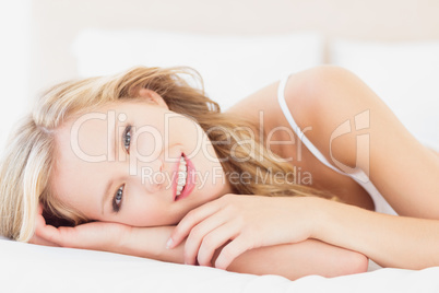 Natural young blonde lying on her bed looking at camera