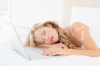 Cute young blonde sleeping beside her laptop