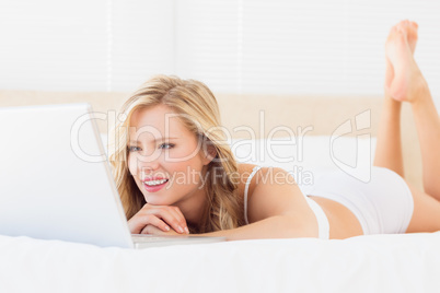 Smiling young blonde watching her laptop