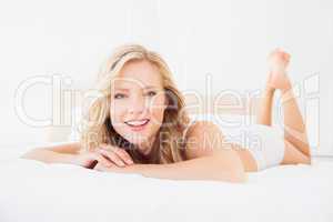 Pretty young blonde smiling at camera on bed