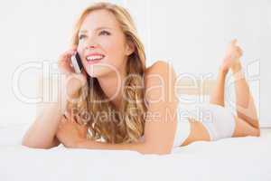 Happy young blonde on the phone lying on bed