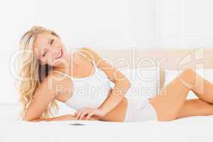 Young blonde lying on bed smiling at camera