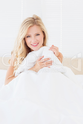 Sexy young blonde covering herself with duvet