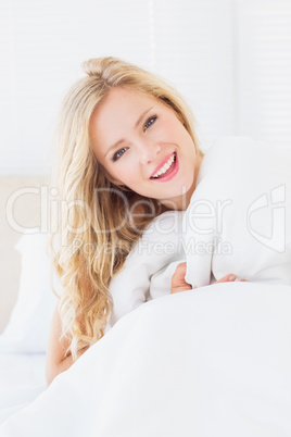 Pretty young woman covering herself with duvet