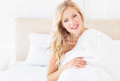 Attractive young woman covering herself with duvet
