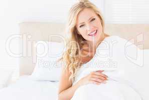 Attractive young woman covering herself with duvet