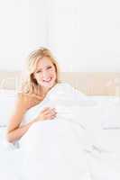 Attractive young blonde covering herself with duvet