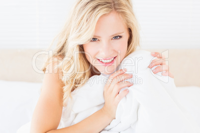 Pretty young blonde covering herself with duvet