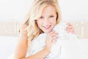 Pretty young blonde covering herself with duvet