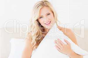 Pretty young blonde covering herself with pillow