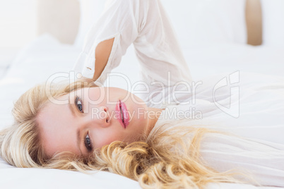 Beautiful young woman in white shirt smiling at camera lying on