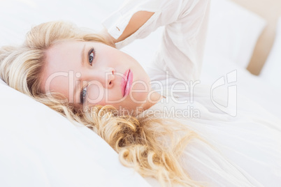 Gorgeous young woman in white shirt smiling at camera lying on b