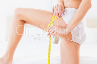 Thin woman measuring her thigh