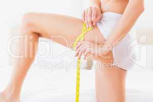 Thin woman measuring her thigh