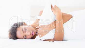 Sleeping brunette lying on bed hugging pillow