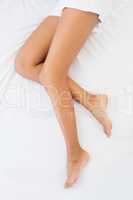 Slim womans legs lying on bed
