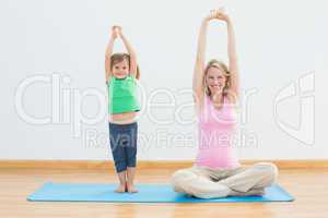 Pregnant mother and daughter doing yoga together
