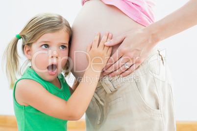 Little girl listening to mothers pregnant belly