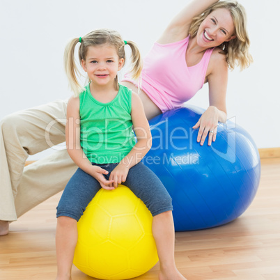 Smiling pregnant woman exercising on exercise ball with young da