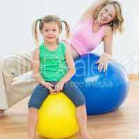 Smiling pregnant woman exercising on exercise ball with young da