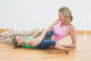 Smiling pregnant woman tickling young daughter