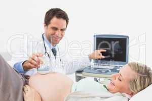Happy doctor showing blonde pregnant woman her baby on sonagram