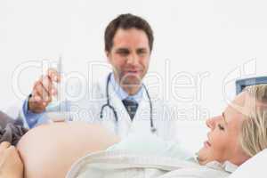 Smiling doctor doing a sonogram scan on pregnant woman