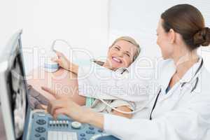 Happy female doctor showing woman her baby on ultrasound