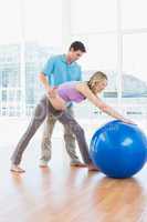 Trainer exercising with pregnant client and exercise ball
