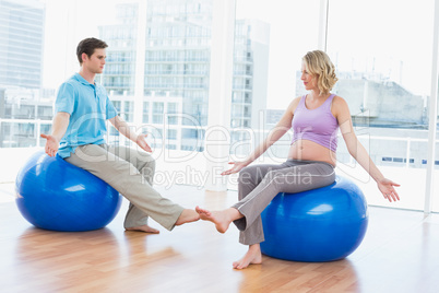 Trainer exercising with pregnant client on exercise balls