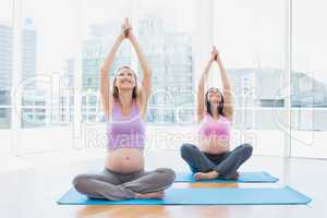 Happy pregnant women in yoga class sitting in lotus pose