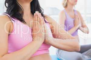 Meditating pregnant women at yoga class in lotus pose