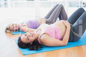 Smiling pregnant women in yoga class lying on mats