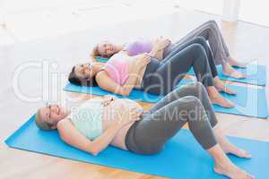 Cheerful pregnant women in yoga class lying on mats