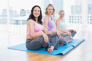 Happy pregnant women sitting in yoga class
