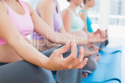 Peaceful pregnant women meditating in yoga class